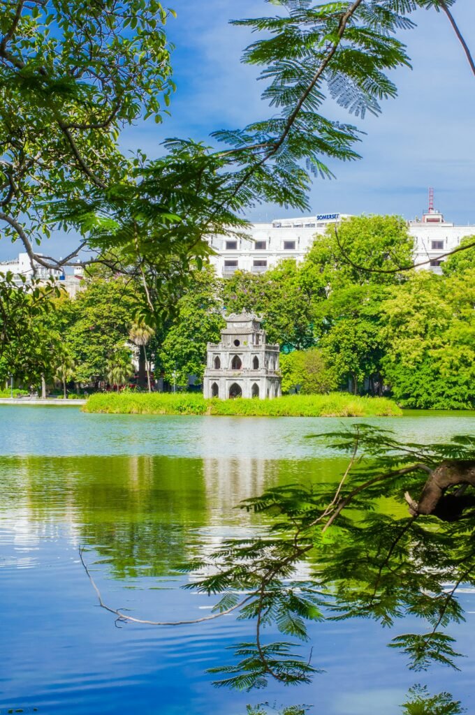 A tree-lined lake in Hanoi with a building in the background