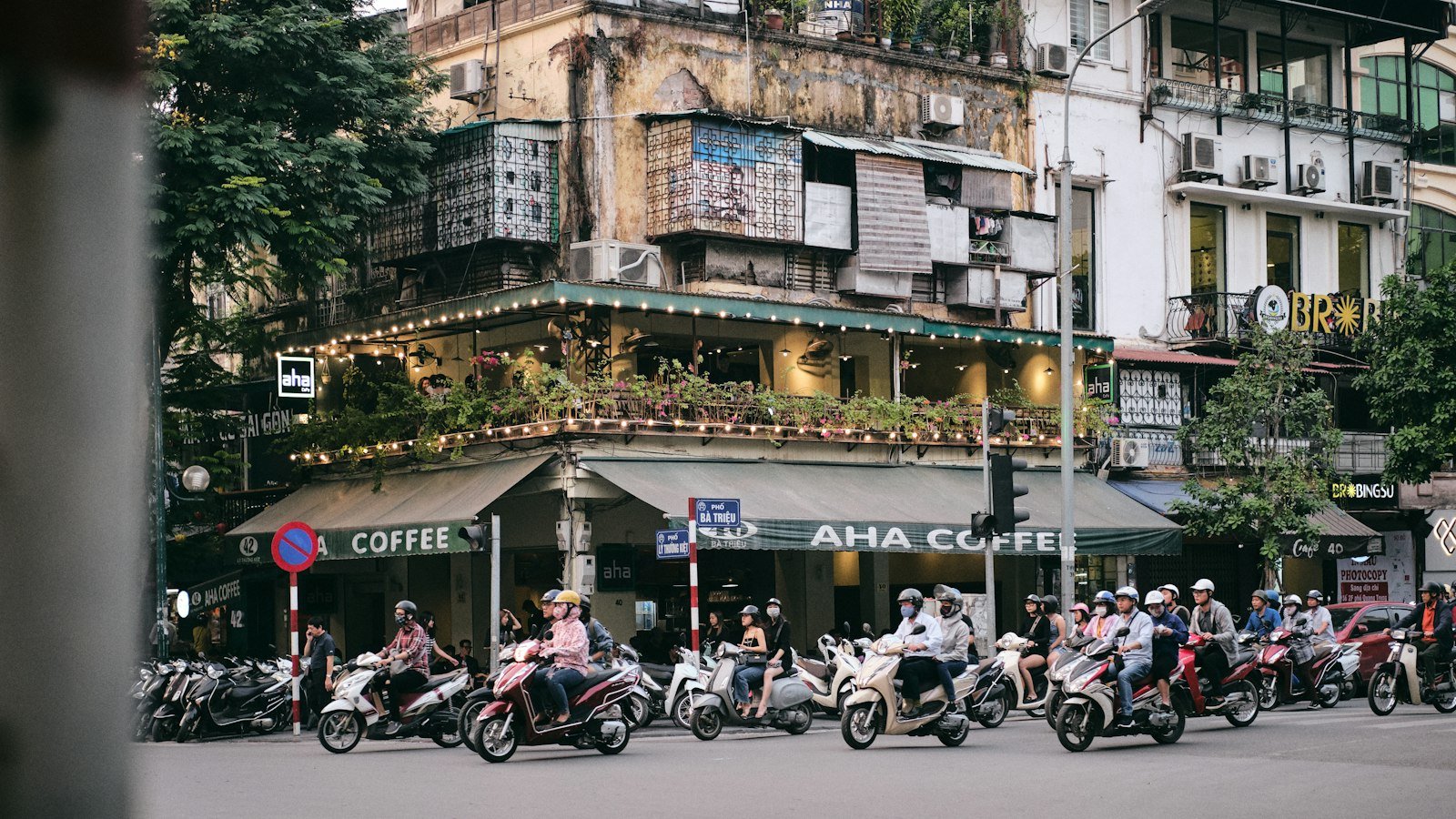 People riding motorbikes past old buildings in Hanoi
