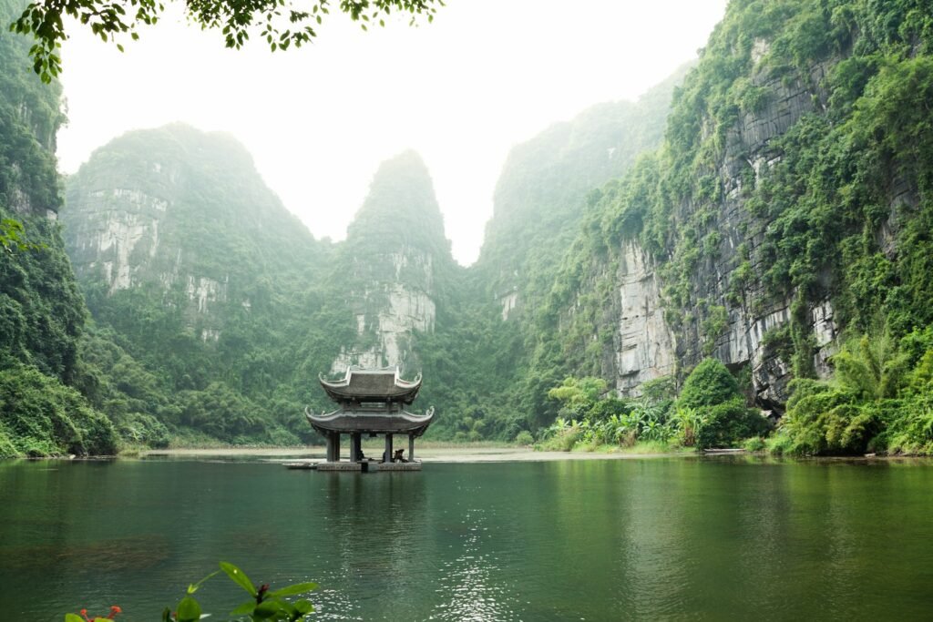 A pagoda by the water surrounded by limestone mountains in Ninh Binh