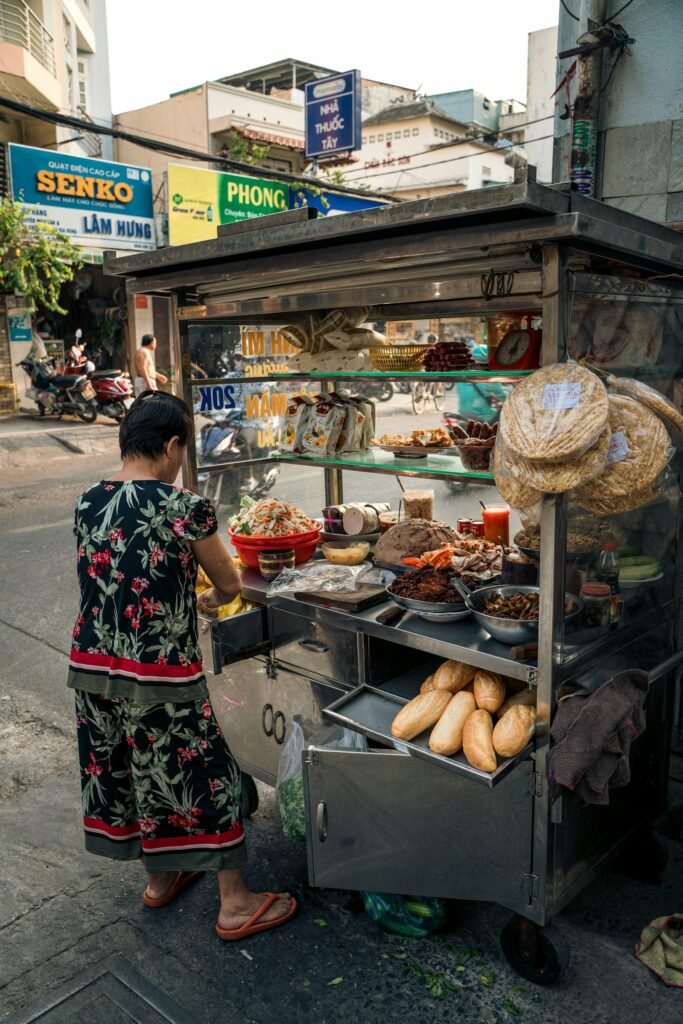 A woman standing at a street food cart in Vietnam