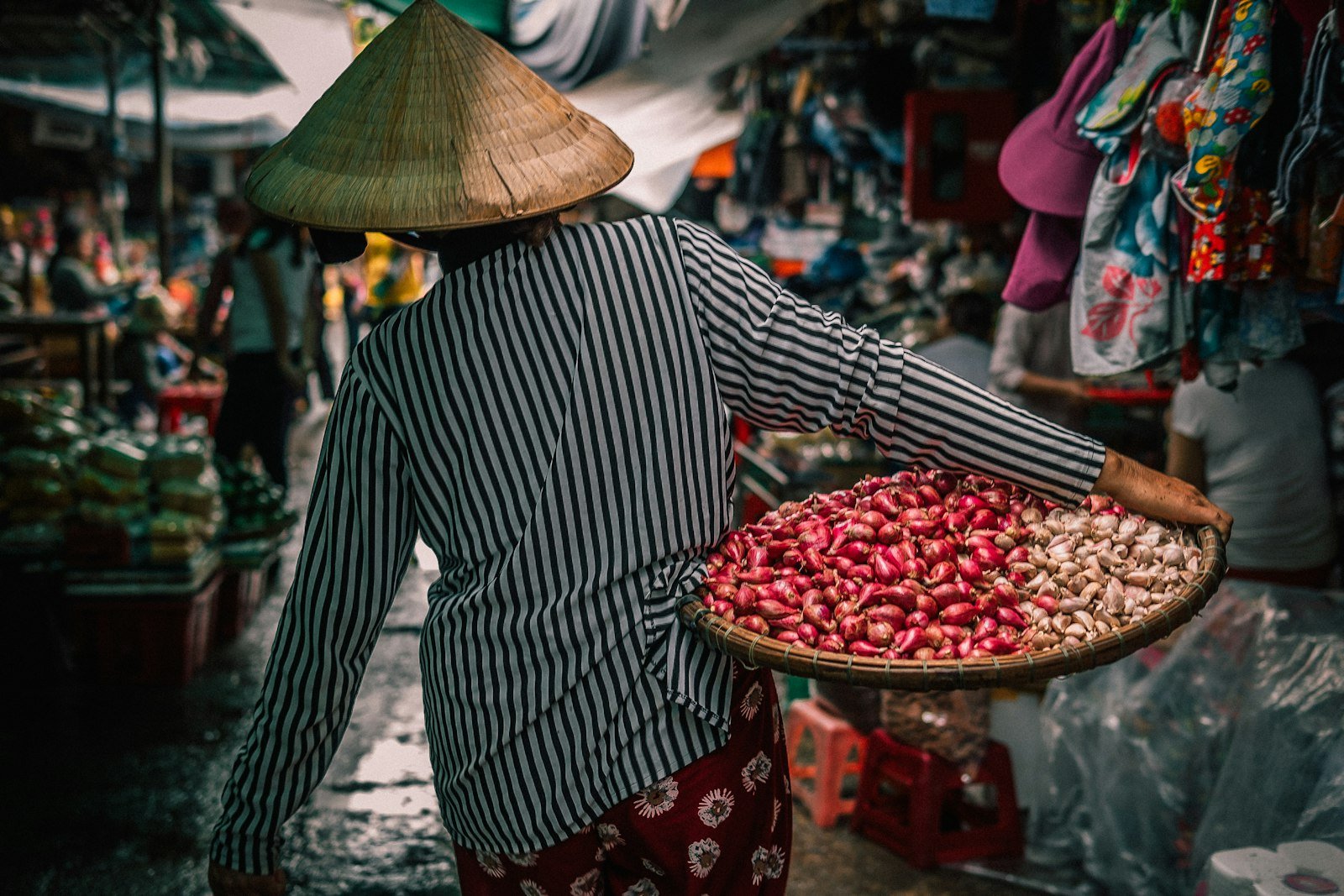 A woman carrying a basket of vegetables at a market