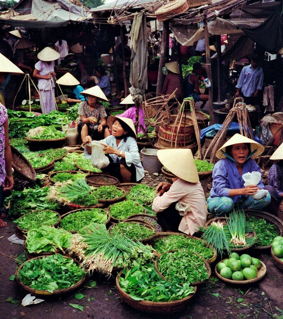 People sitting on small stools at a street market