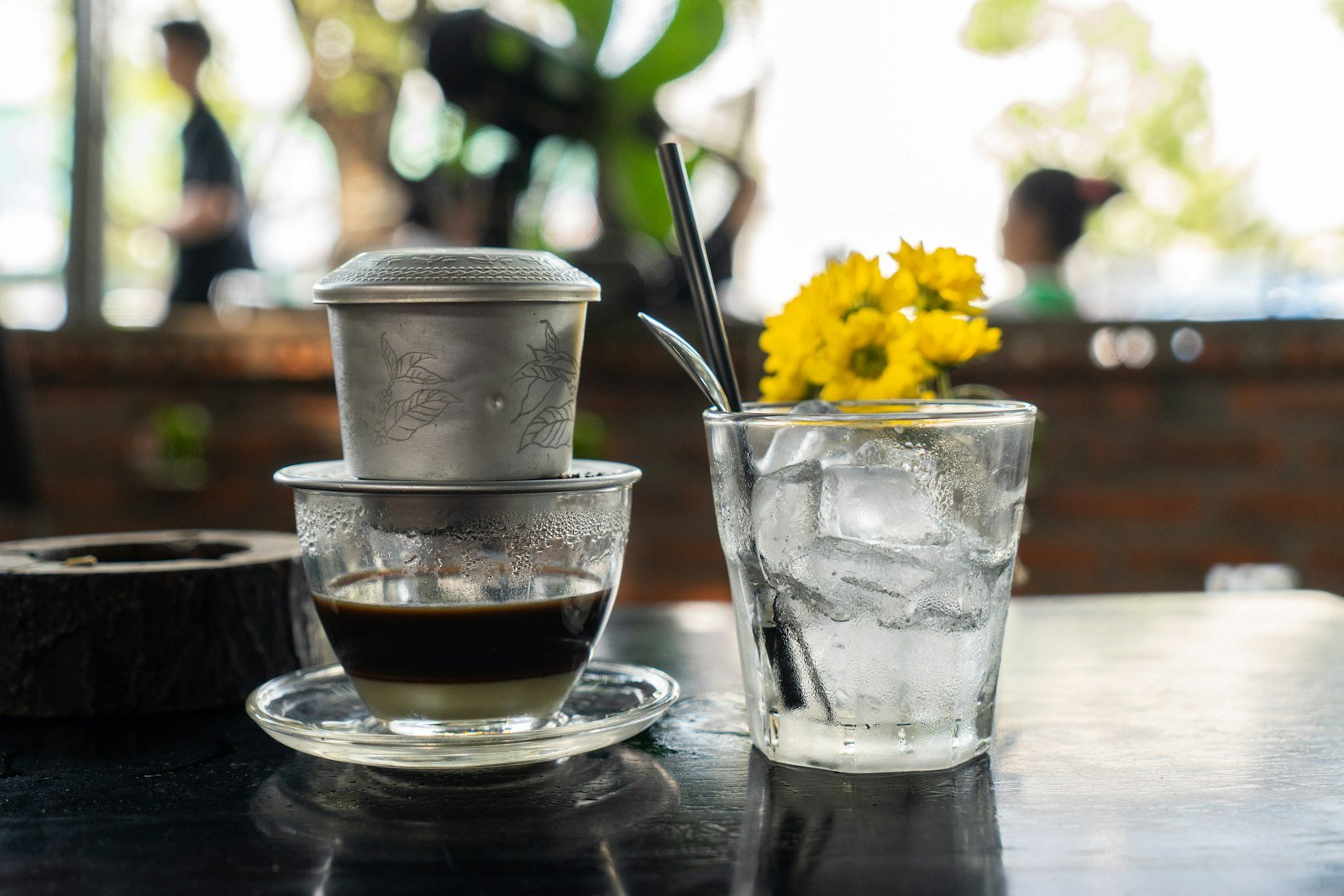 A Vietnamese coffee with a glass of iced tea on a table